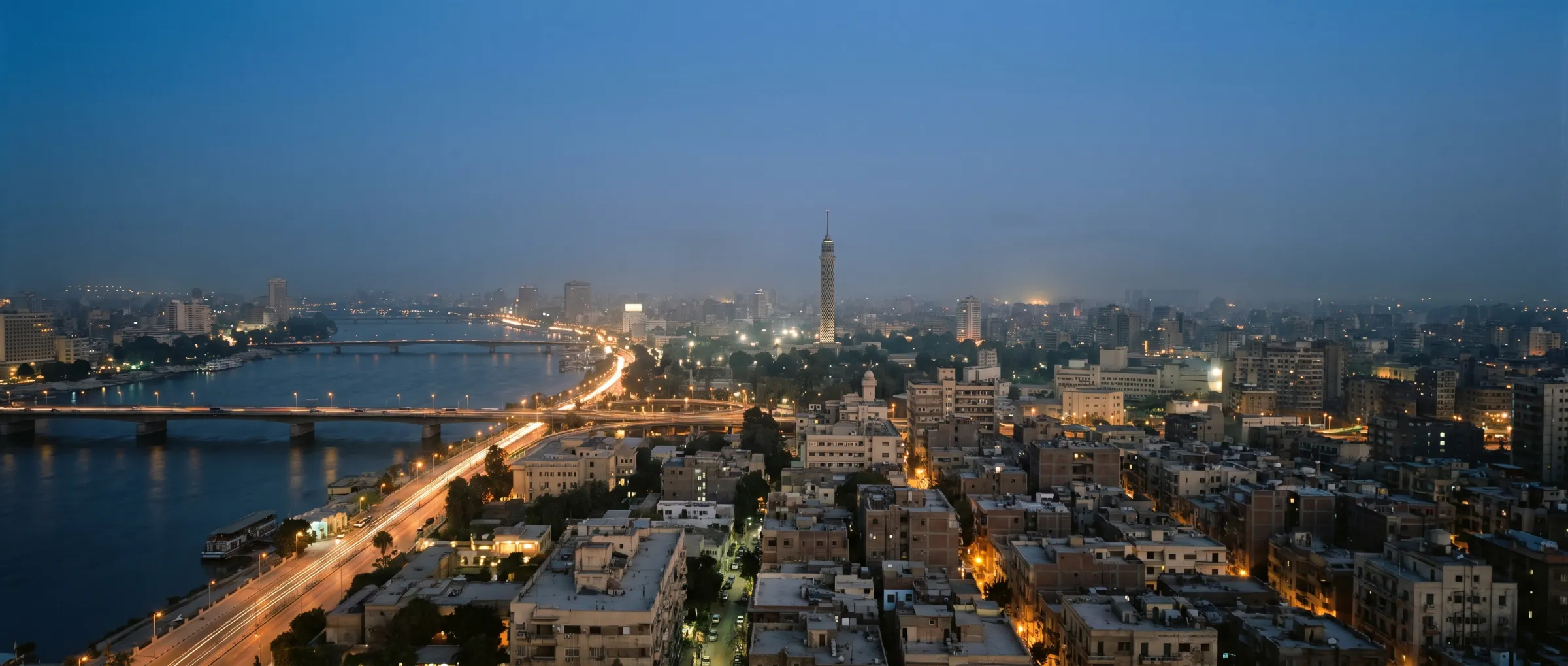 Cairo at dusk, the Nile crossed by lit bridges carrying traffic
